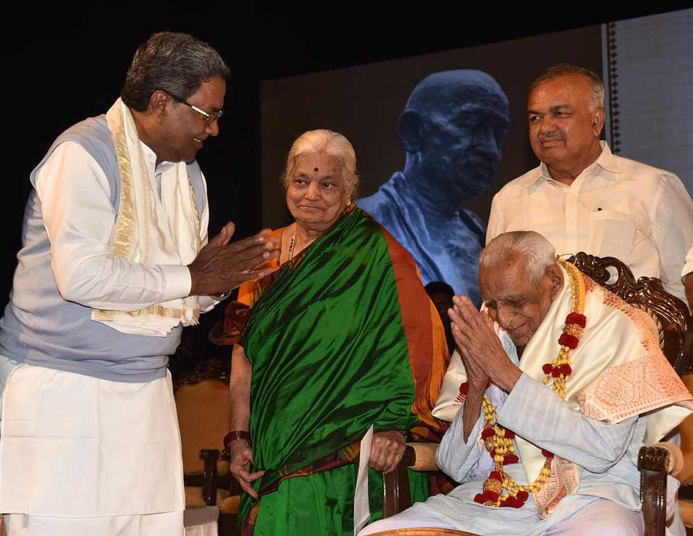Chief Minister Siddaramaiah presents Gandhi Seva Award to freedom fighter H S Doreswamy in Bengaluru on Monday. Doreswamy's wife Lalitha and Home Minister Ramalinga Reddy are seen. DH Photo.