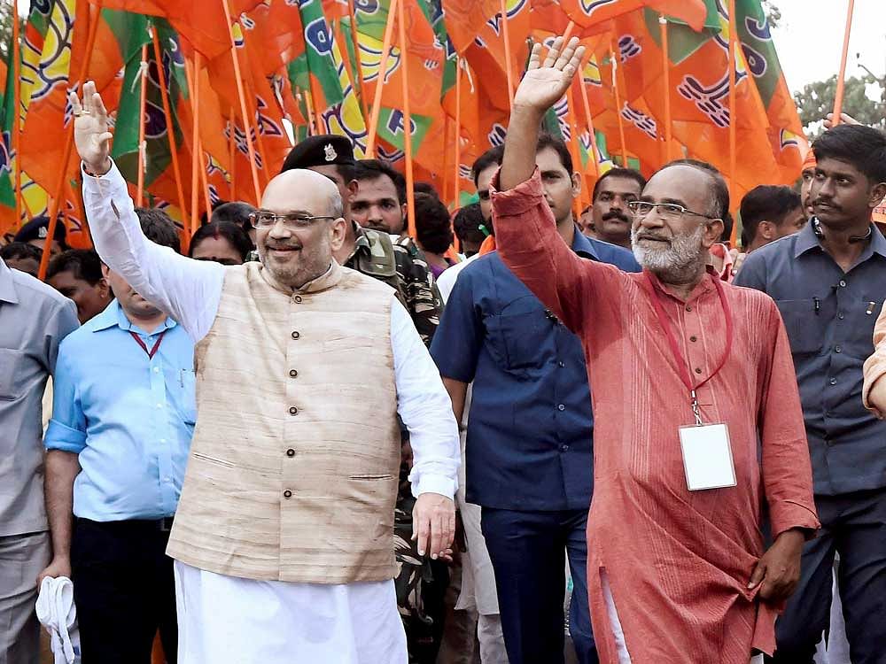 BJP National President Amit Shah and Tourism Minister Alphonse Kannanthanam waves to the crowed during the party's 'Janaraksha Yathra' at Payyannur in Kannur on Tuesday. PTI Photo