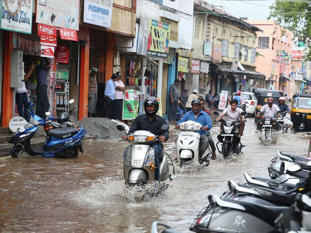 Two-wheelers wade through the flooded Thyagaraja Road in Mysuru on Thursday.  PHOTO / SPECIAL ARRANGEMENT