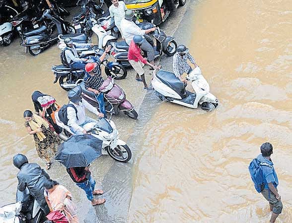 Motorists struggle to move on the flooded K H Road in Shanthinagar. DH PHOTO