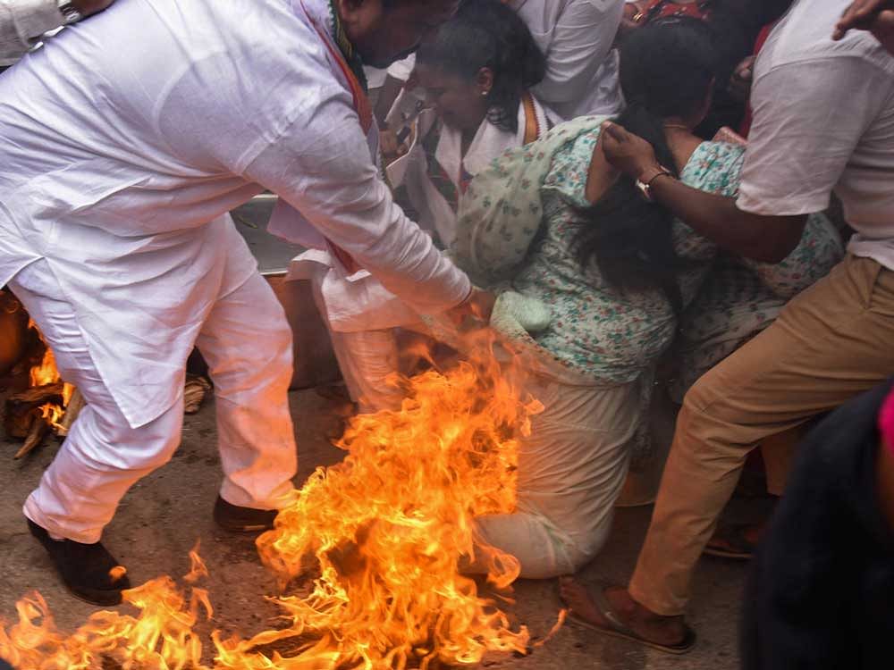 Youth Congress workers try to save their leader Sumantha whose clothes were engulfed in fire during a protest in Bengaluru on Friday.