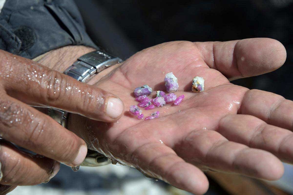 This photograph taken on September 20, 2017 shows a Pakistani labourer displaying ruby gemstones after finding them in pieces of rocks outside a mine at a mountain in the Kashmiri town of Chitta Katha in Upper Neelum Valley in Pakistan-administered Kashmir. The people of Pakistani Kashmir are sitting on a treasure chest: Millions of rubies, estimated to be worth up to half a billion dollars, are lying beneath them. But a lack of investment in infrastructure and archaic tools and techniques are hampering efforts to tranform the area into a significant player in the gem industry. / AFP PHOTO