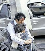 A survivor, along with his daughter, sits beside rubble in the Qinghai province. AFP
