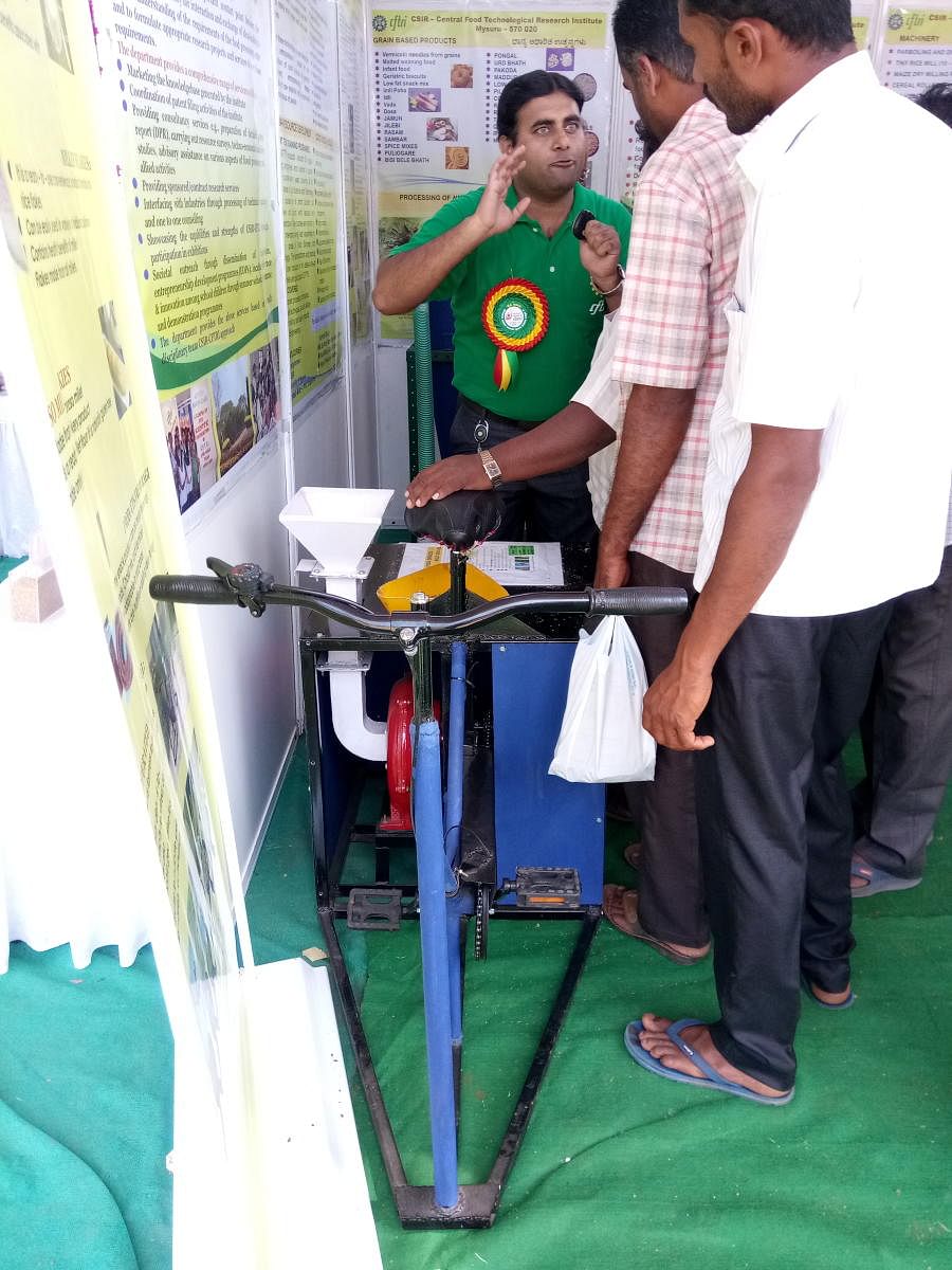 Central Food Technological Research Institute officials explain to farmers about the 'Pedal Operated Millet De-huller' during the Organic and Millets Mela, at Scouts and Guides Grounds near the Deputy Commissioner's office in Mysuru on Wednesday.