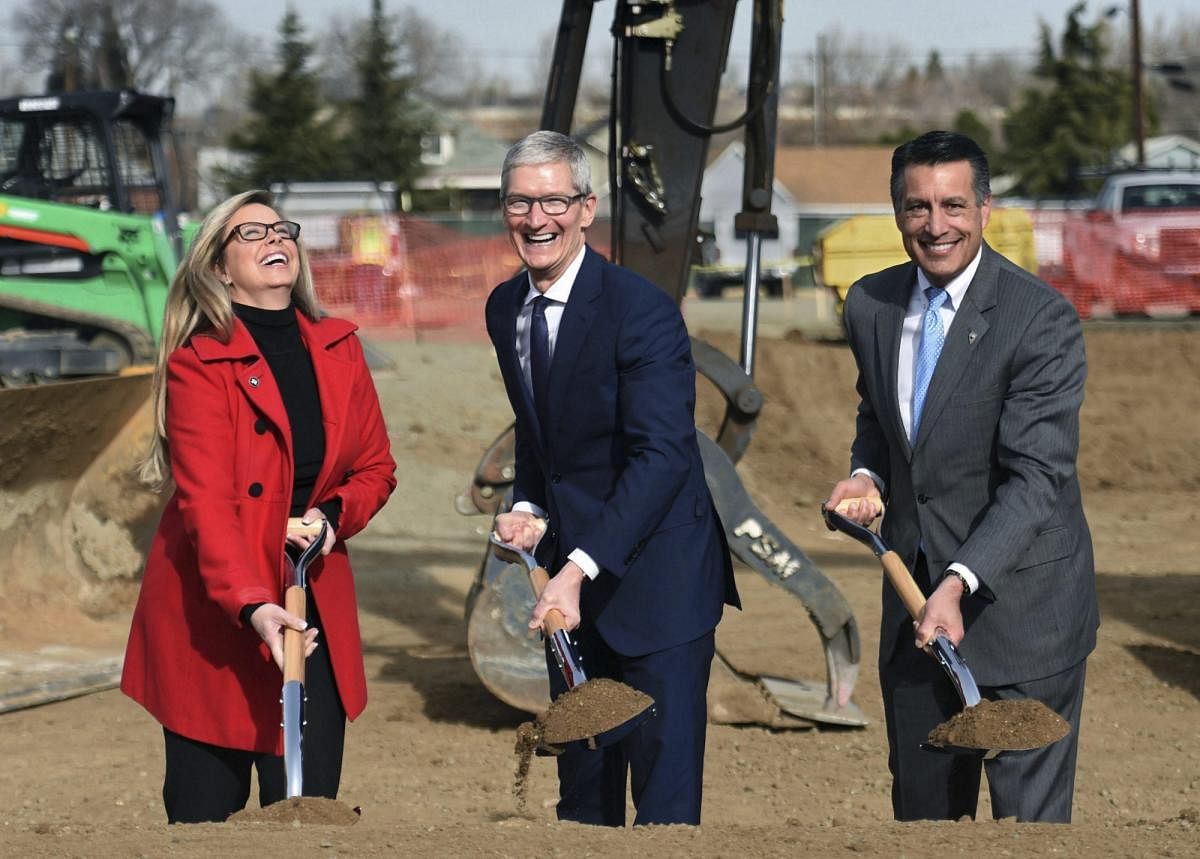 Reno : Apple CEO Tim Cook, center, laughs with Reno Mayor Hillary Schieve, left, and Nevada Gov. Brian Sandoval during a groundbreaking ceremony celebrating a new Apple warehouse on Wednesday, Jan. 17, 2018, in Reno, Nev. AP/PTI(AP1_18_2018_000008A)