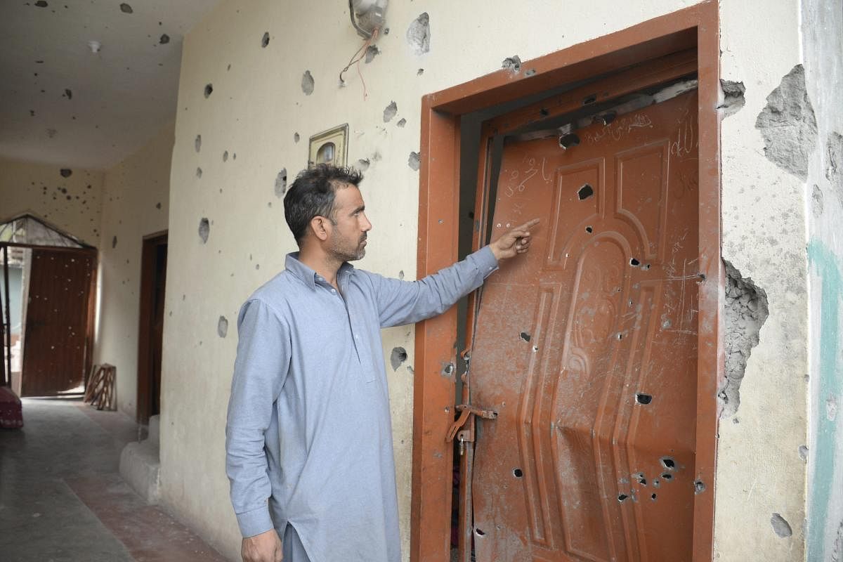 Pakistani Kashmiri villager Matloob Hussain Shah shows shrapnel-riddled door and walls allegedly caused by rockets fired across the border in Mandhol situated at the Line of Control between Pakistan and Indian Kashmirs, Friday, Feb. 23, 2018. Pakistan's foreign ministry says Indian troops opened fire in the disputed Himalayan region of Kashmir, killing villager on the Pakistani side of the boundary.