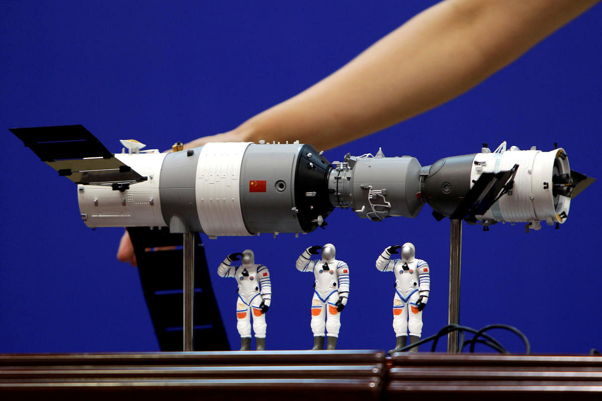 A model of the Tiangong-1 space lab module (left), the Shenzhou-9 manned spacecraft (right) and three Chinese astronauts is displayed during a news conference. REUTERS FILE PHOTO
