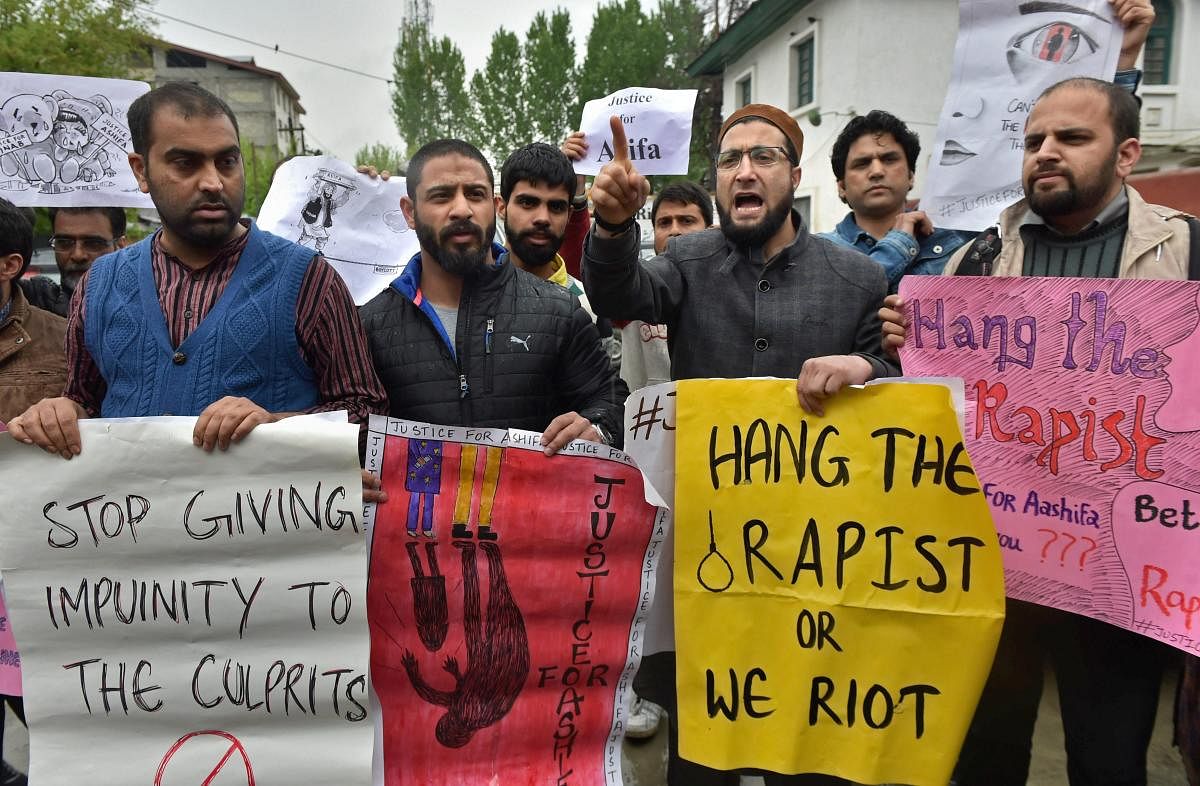 A group of people display placards and raise slogans during a protest demanding justice for eight year old Ashifa of Kathua, Jammu, who was allegedly gangraped and murdered, in Srinagar on Tuesday. PTI Photo