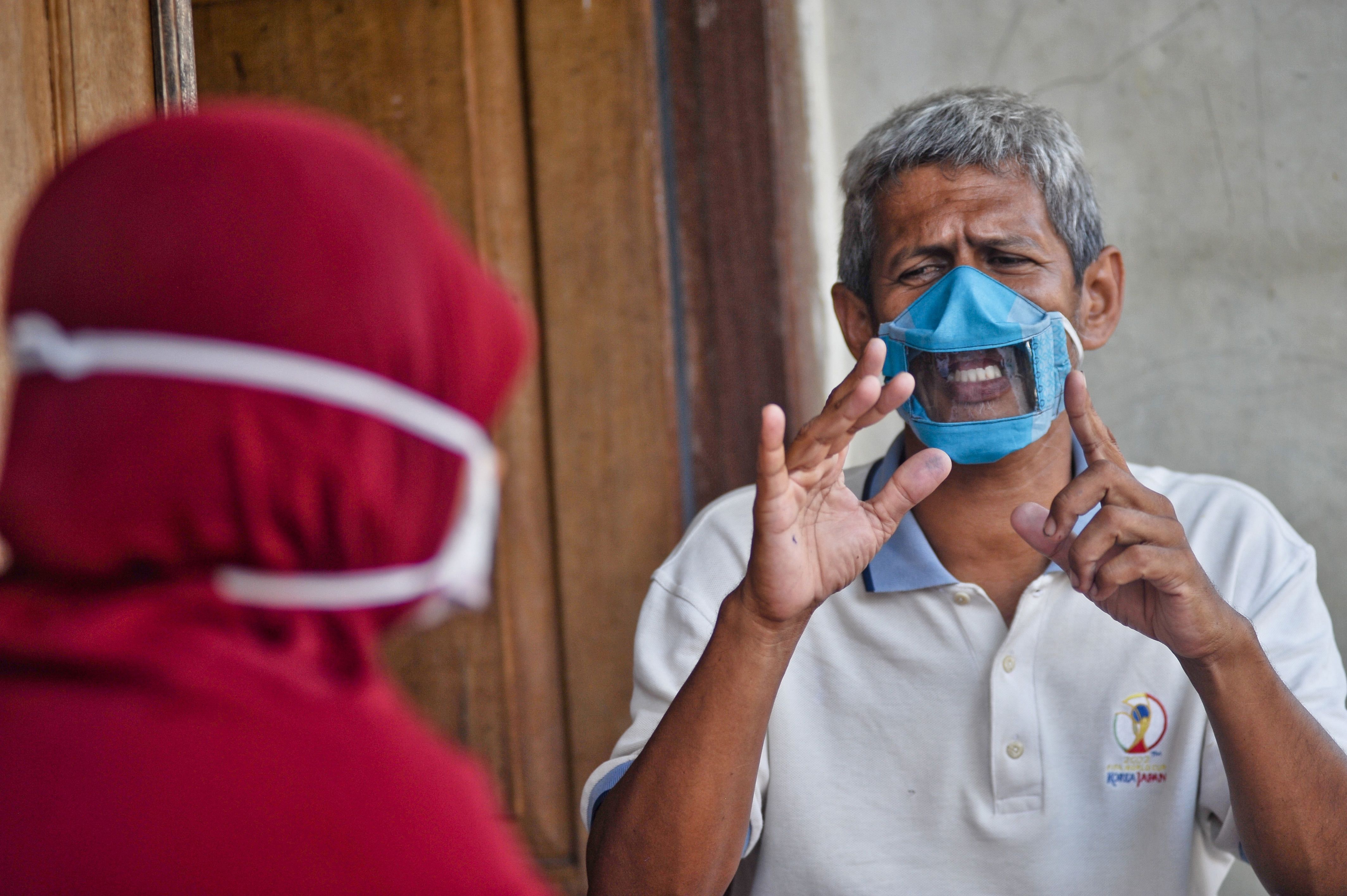 Dwi Rahayu (L) and her husband Elfiandi who are deaf and mute communicate while wearing face masks with a transparent cover in Yogyakarta (AFP)