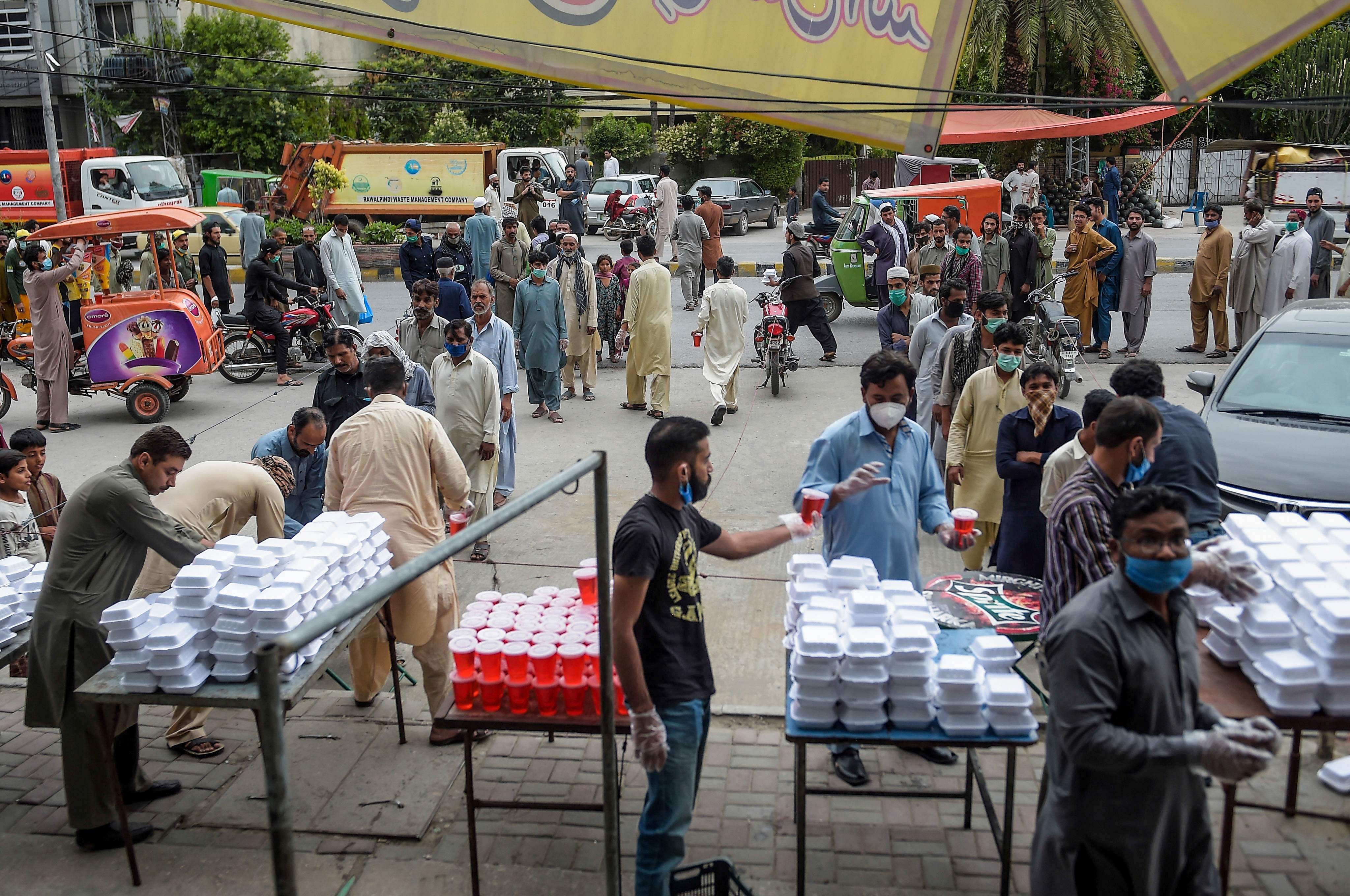 People in need receive free food during a distribution organised by a shop owner of the market on a street after the government eased the nationwide lockdown imposed as a preventive measure against the COVID-19 in Pakistan. (PTI Photo)