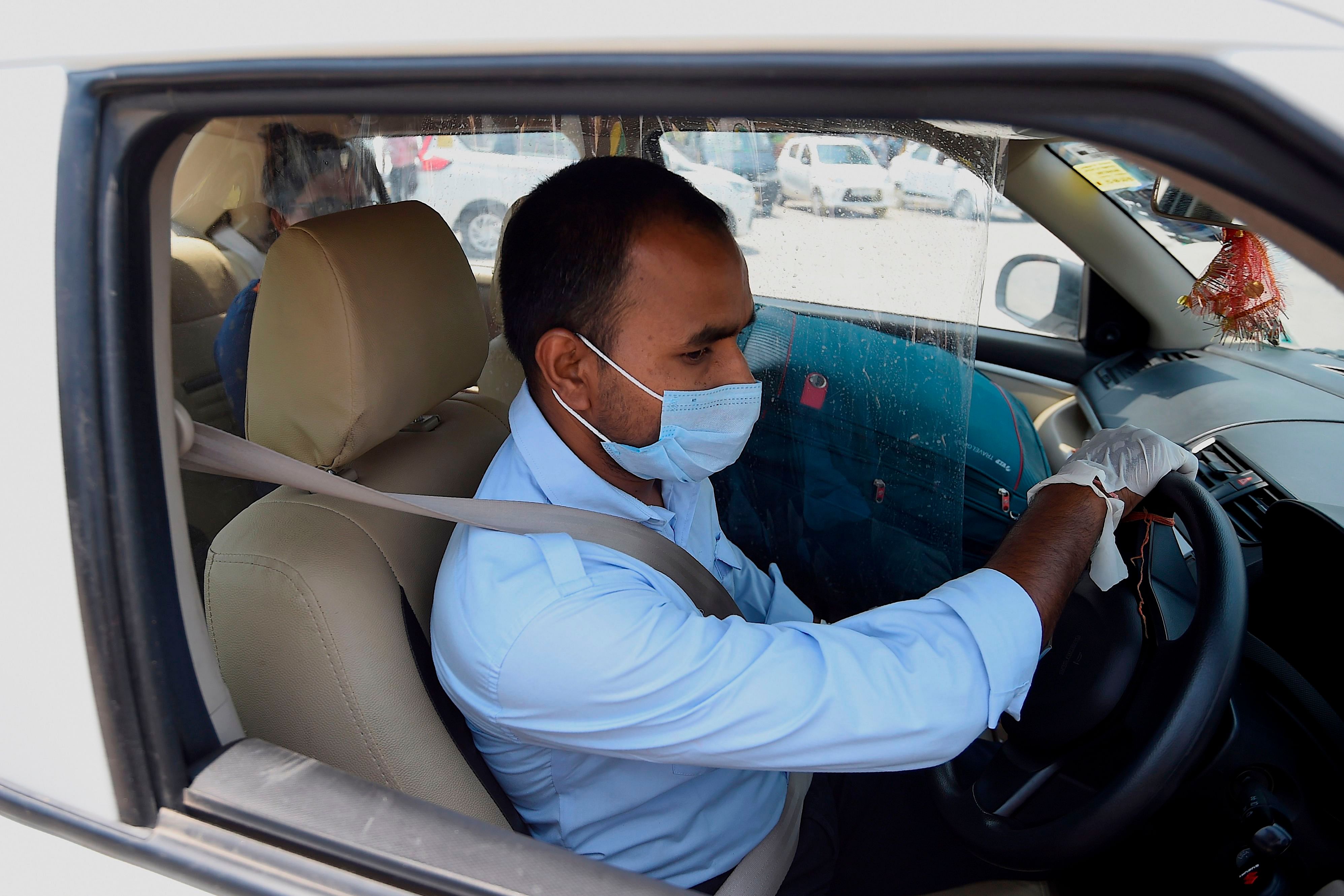 A taxi driver wearing a facemask and gloves is seen at a railway station after the government eased restrictions imposed as a preventive measure against the spread of the COVID-19 Coronavirus in New Delhi (AFP photo)