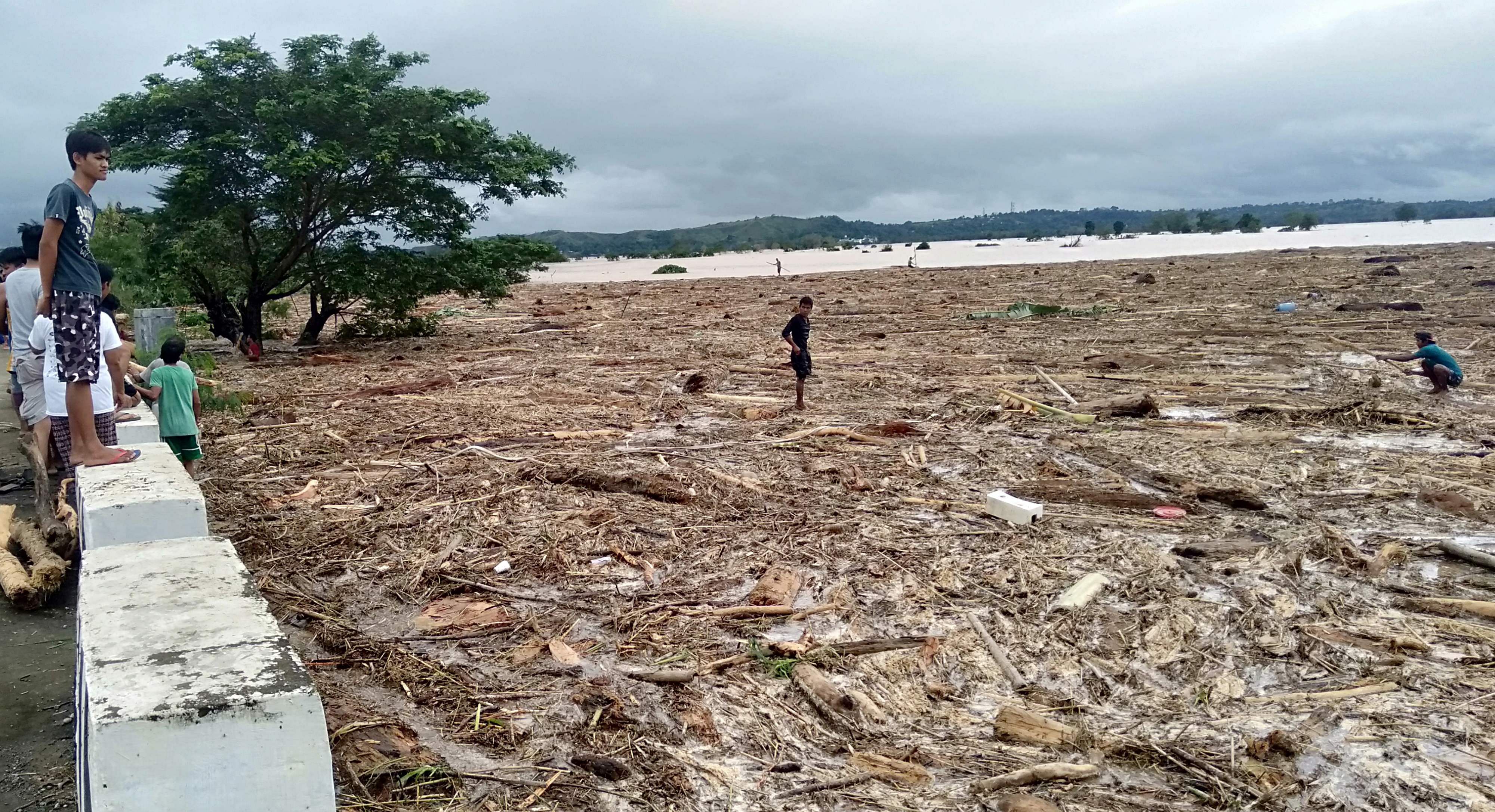 Residents walk on a rice field with washed up debris caused by Typhoon Kammuri in Ilagan. (AFP Photo)