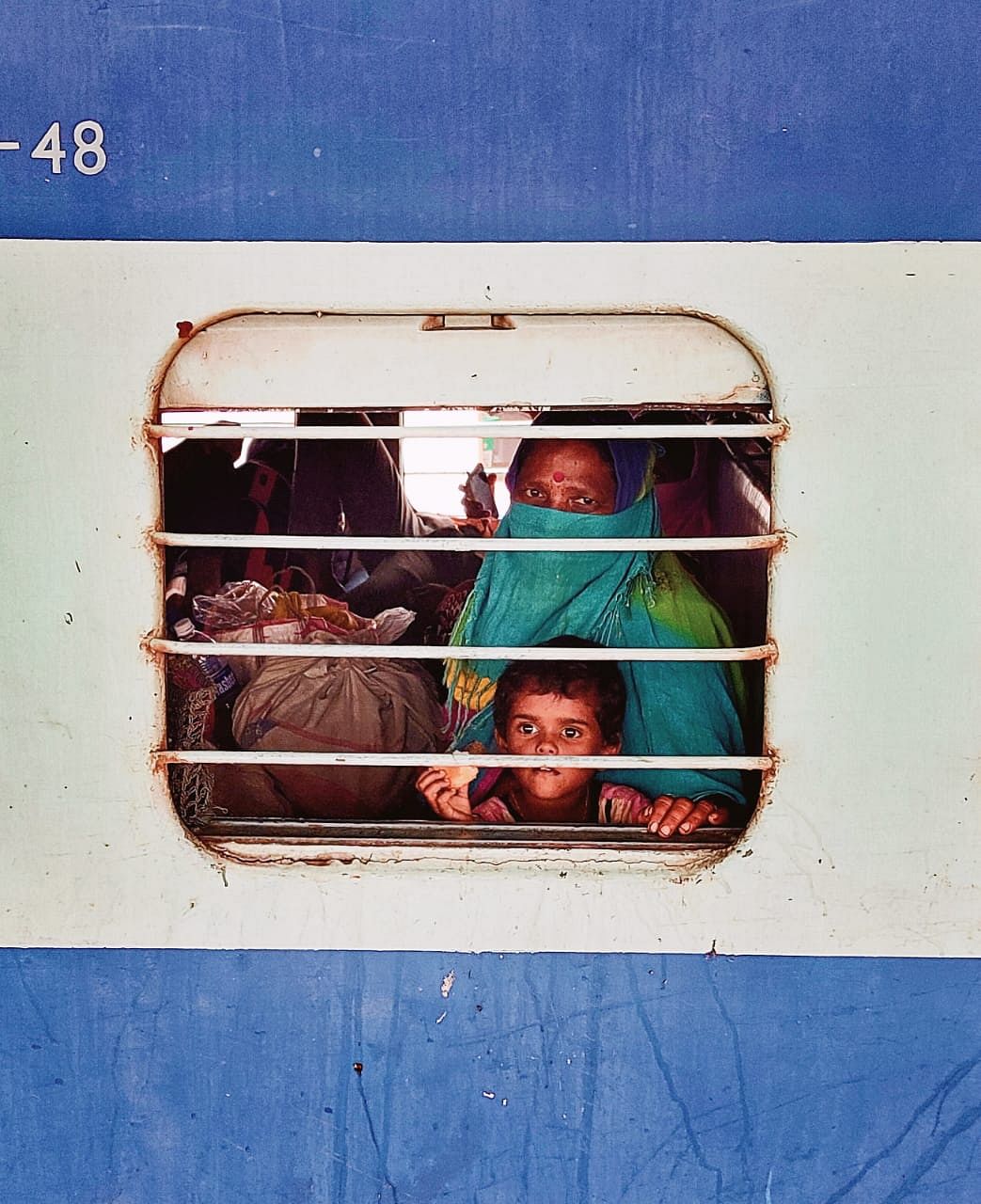 A migrant labourer with her child looks from inside a train to Azamgarh before the departure at Ballari railway station on Sunday