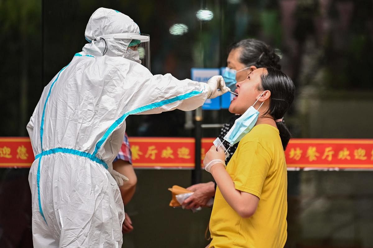 A medical worker takes a swab sample from a man to be tested for the COVID-19 coronavirus next to a street in Wuhan (AFP Photo)