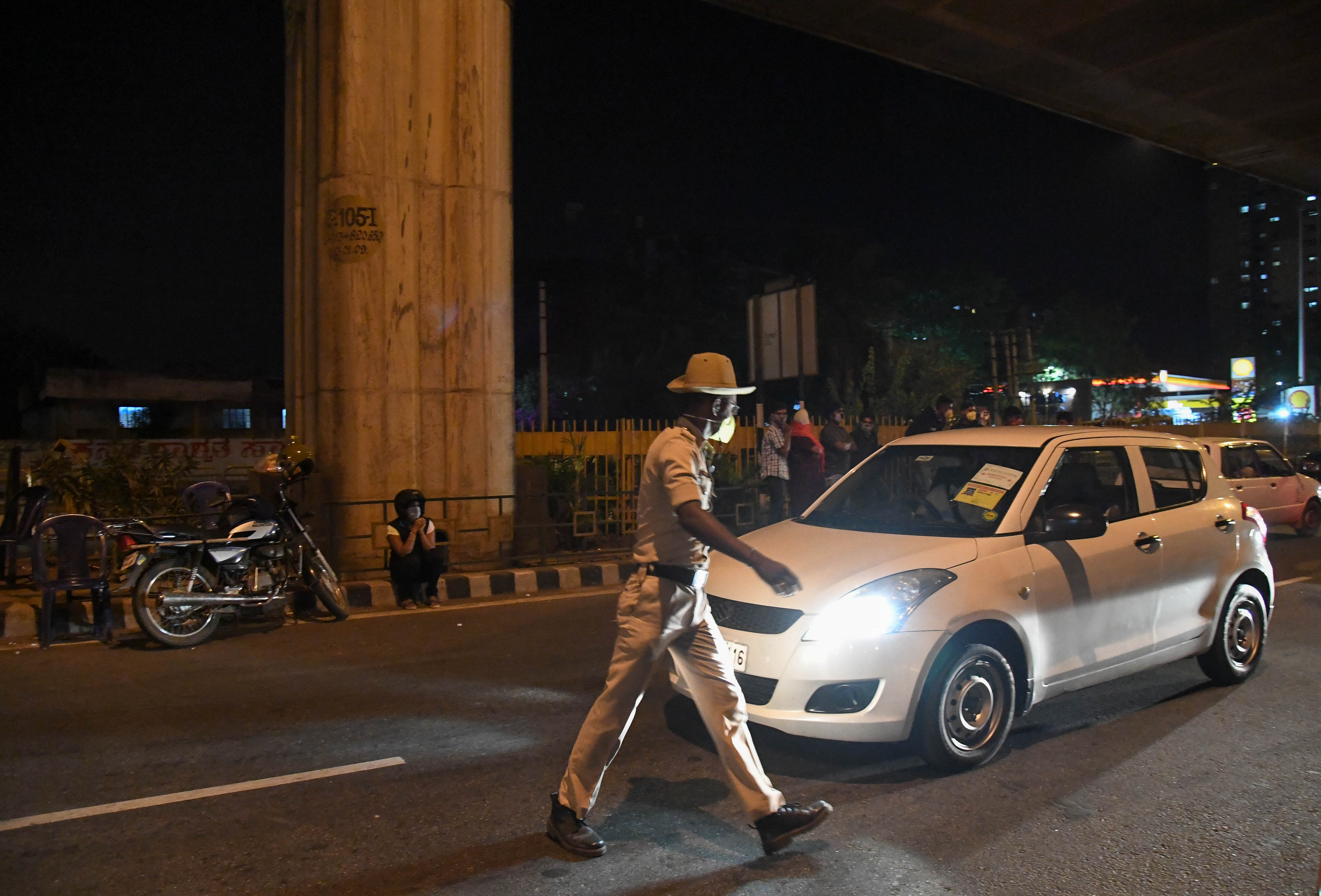 Police personnel stop commuters for venturing out of their homes in the night, during a nationwide lockdown, imposed in the wake of coronavirus pandemic. (DH Photo)