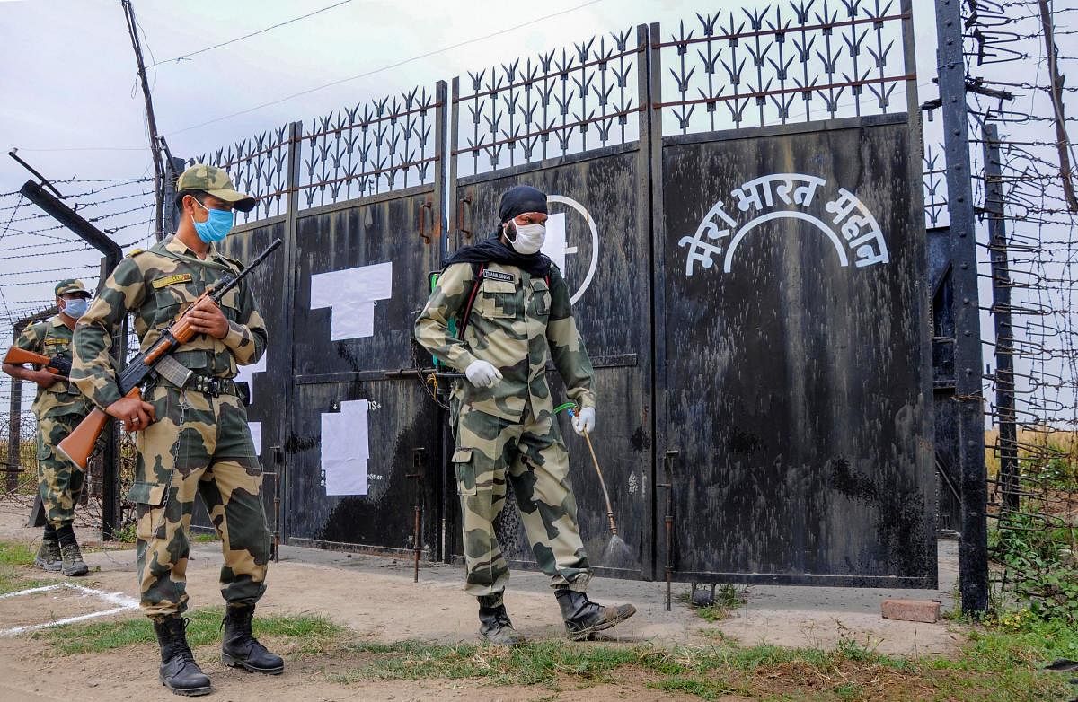 A BSF soldier sprays disinfectant near the border fencing (PTI Photo)