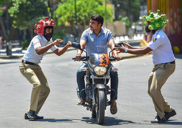 Two policeman wearing coronavirus-themed helmets charge another ríding a bike during an awareness programme amid the nationwide lockdown in the wake of novel coronavirus pandemic, in Bengaluru, Tuesday, Mar 31, 2020. (PTI Photo/Shailendra Bhojak)