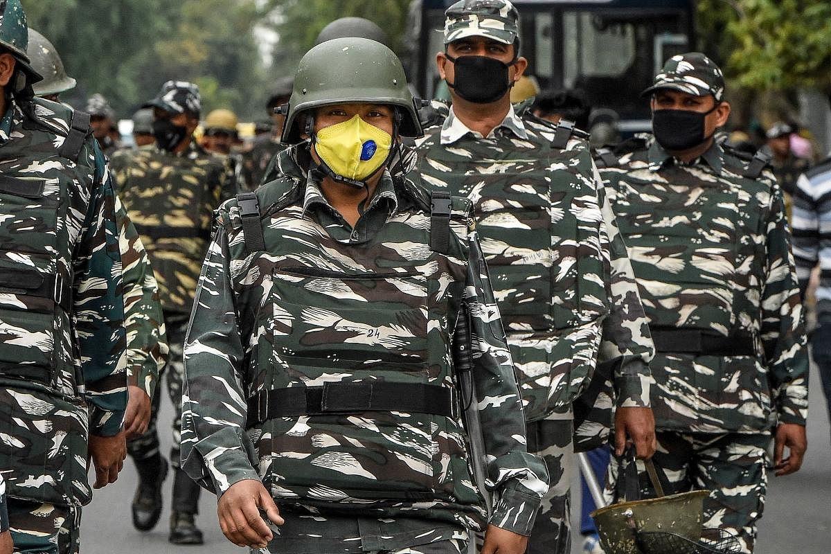Security personnel wear facemasks as they accompany a peace march on a road in New Delhi. (AFP Photo)