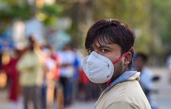 A man is seen wearing a mask, as a precaution against the spread of the coronavirus, while buying essential goods at a market in Ghaziabad. (Credit: PTI Photo)
