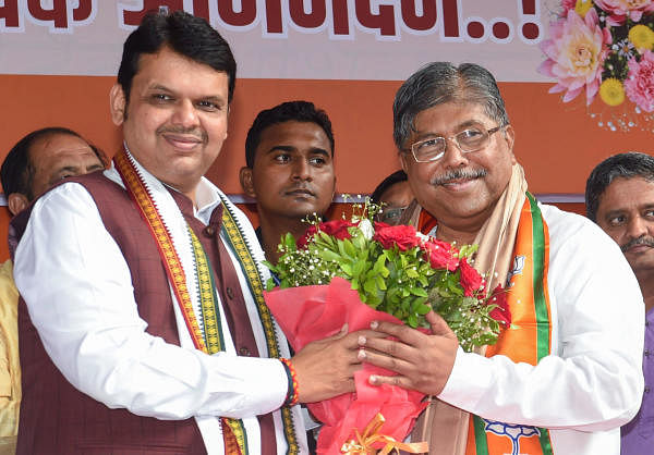 Chief Minister Devendra Fadnavis greets the new BJP State President Chandrakant Patil, during a felicitation event in Mumbai. (PTI photo)