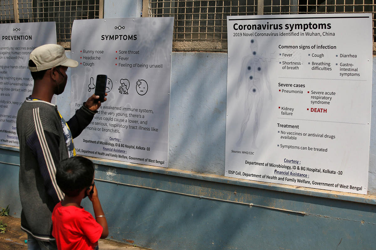A man uses his mobile phone to take photographs of posters carrying messages on symptoms of coronavirus disease inside hospital premises in Kolkata. (Reuters photo)