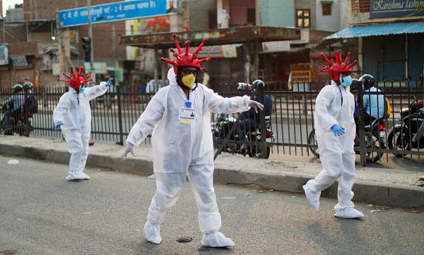 Artists wearing coronavirus-shaped helmets and protective suits walk on a street as they request people to stay at home during an extended lockdown to slow the spread of the coronavirus disease (COVID-19) in New Delhi, India, April 30, 2020. (Credit: Reuters Photo)