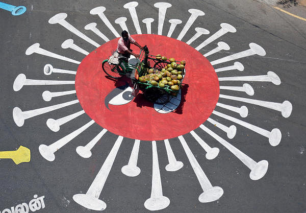 A man selling coconuts rides his trishaw on a graffiti on a road depicting the coronavirus as an attempt to raise awareness about the importance of staying at home during a 21-day nationwide lockdown to slow the spreading of the coronavirus disease (COVID-19), in Chennai. (Credit: Reuters Photo)