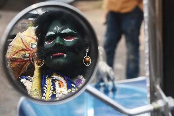 The reflection of a man dressed as Hindu deity of death Yamaraj (R) to raise awareness about the coronavirus is seen on the wing mirror of a vintage car during a government-imposed nationwide lockdown as a preventive measure against the COVID-19 coronavirus, in Kolkata on April 24, 2020. (Credit: AFP Photo)