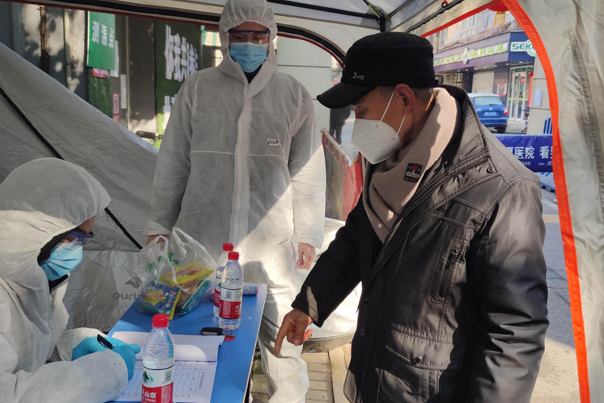 Volunteers in protective suits help a man with registration at a checkpoint of a residential compound, following the outbreak of the novel coronavirus in Wuhan. (Reuters Photo)