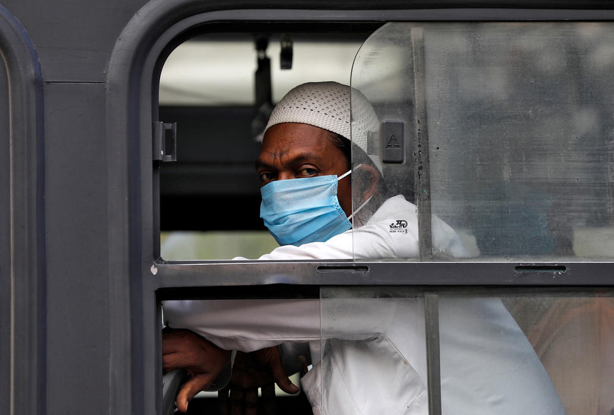 A man wearing a protective mask sits inside a bus that will take him to a quarantine facility, amid concerns about the spread of coronavirus disease (COVID-19), in Nizamuddin area of New Delhi, India, March 30, 2020. Credit: Reuters Photo