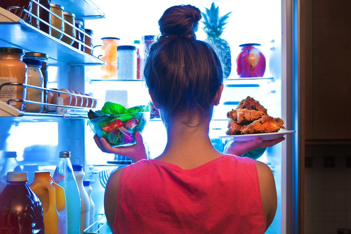 Young Woman Making Choices for a Healthy Salad or Junk Food Fried Chicken. (Getty Image)