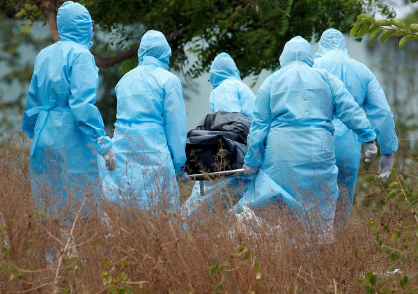 Municipal workers and relatives wearing protective suits carry the body a woman who died due to the coronavirus disease (COVID-19), for her burial at a graveyard in Chennai, India. (Credit: Reuters Photo)