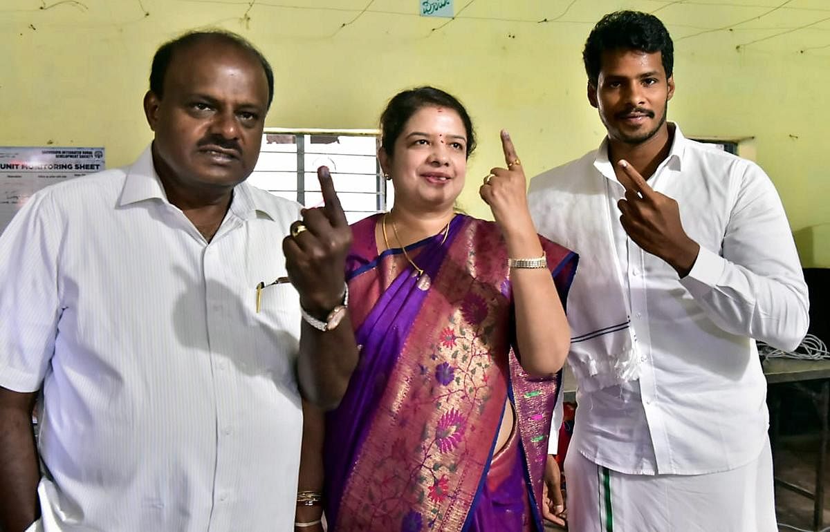 Karnataka Chief Minister HD Kumaraswamy along with wife Anitha Kumaraswamy (C) and son Nikhil Gowda (R) show their finger marked with indelible ink after casting vote for the second phase of the general elections, at a polling station, Kethiganahalli in Ramanagara district, Thursday. PTI photo
