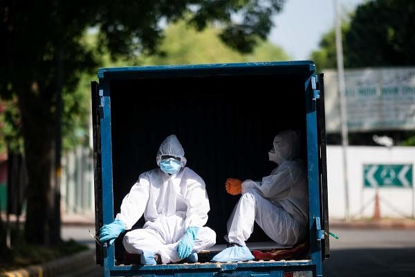 Men wearing Personal Protective Equipment (PPE) ride in the back of a vehicle along a street during a government-imposed nationwide lockdown to prevent the spread of the COVID-19 coronavirus in New Delhi on May 4, 2020. (AFP Photo/Jewel Samad)