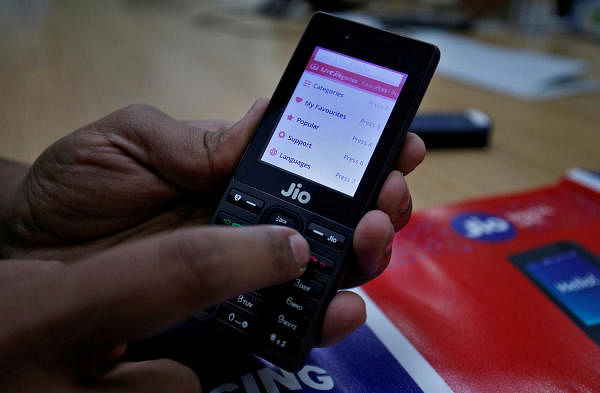 A sales person displays features of JioPhone as he poses for a photograph at a store of Reliance Industries' Jio telecoms unit. (Reuters photo)