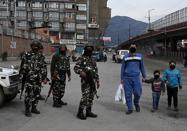 A family wearing facemasks walk along a street during a government-imposed nationwide lockdown as a preventive measures against the COVID-19 coronavirus, in Srinagar on April 3, 2020. (Credit: AFP Photo)