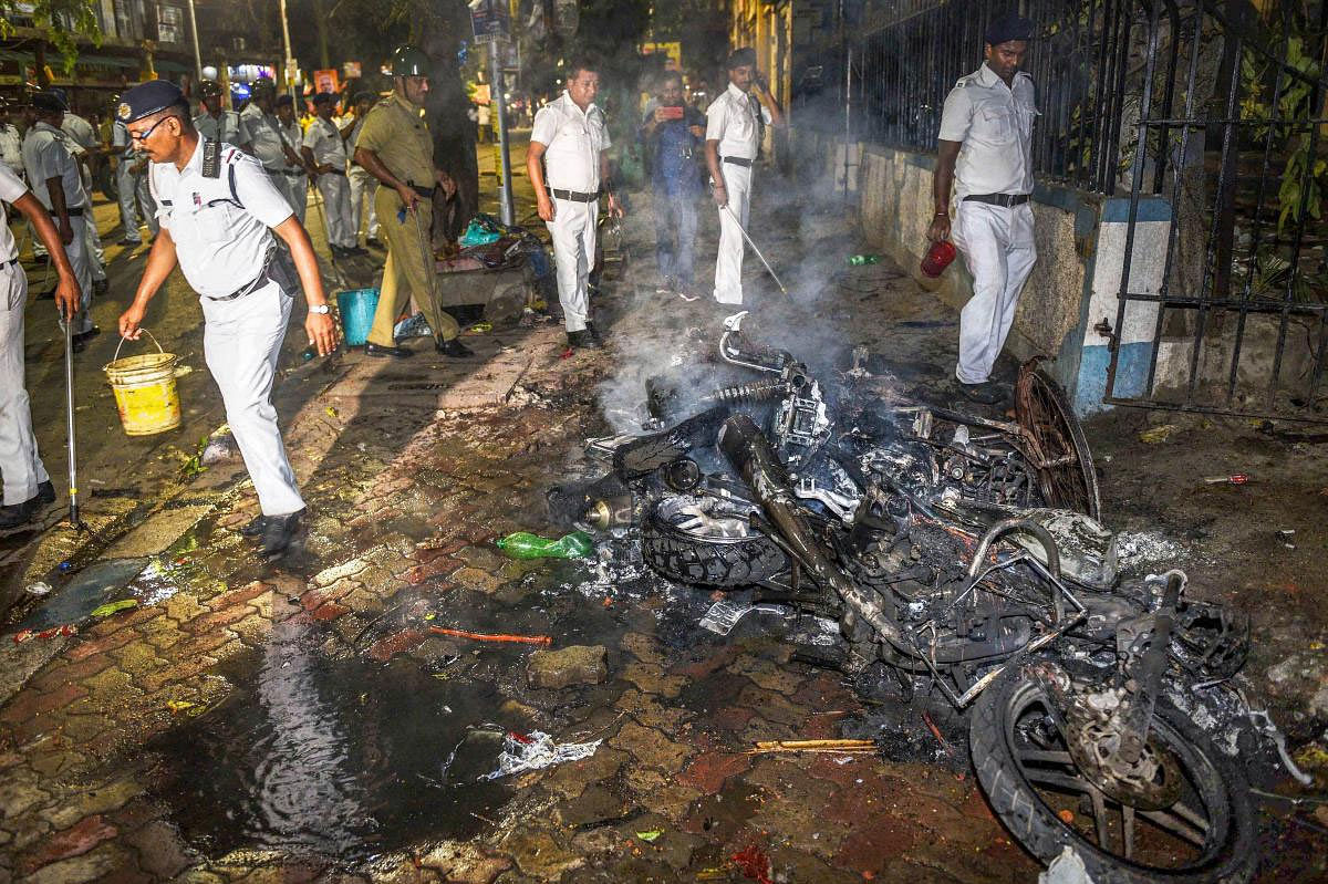 Police personnel douse burning vehicles caused by a mob during BJP President Amit Shah's election roadshow for the last phase of Lok Sabha polls, in Kolkata, Tuesday, May 14, 2019. (PTI Photo)