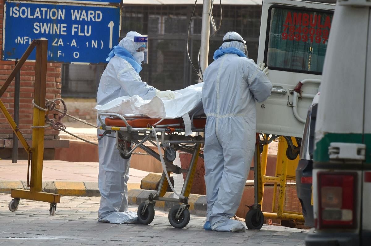 Health workers wearing protective suits shift to a van the body of a coronavirus victim, at LNJP Hospital in New Delhi (PTI Photo)