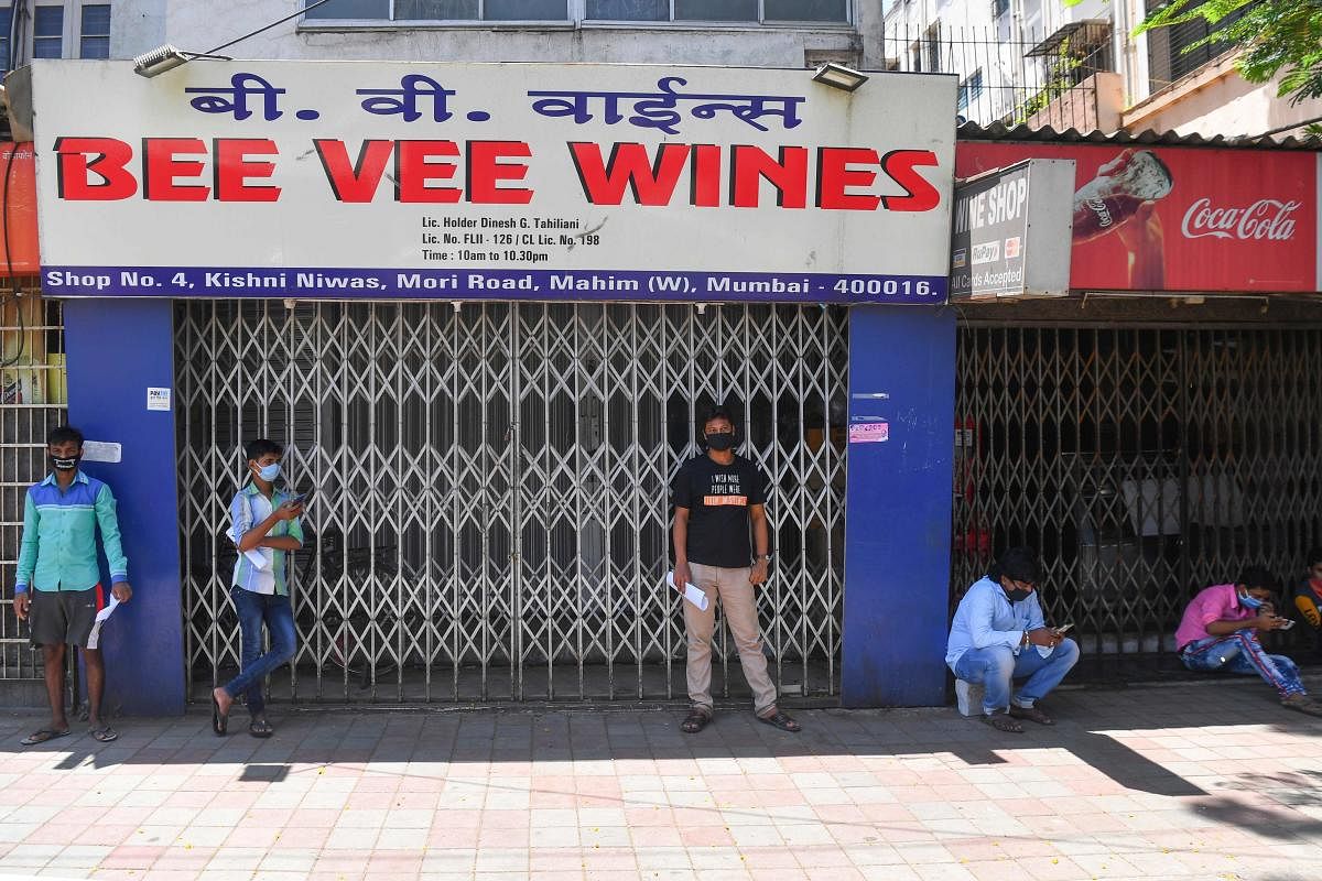 People wait outside a closed liquor shop after the government eased a nationwide lockdown imposed as a preventive measure against the COVID-19 coronavirus, in Mumbai on May 4, 2020. Credit: AFP Photo