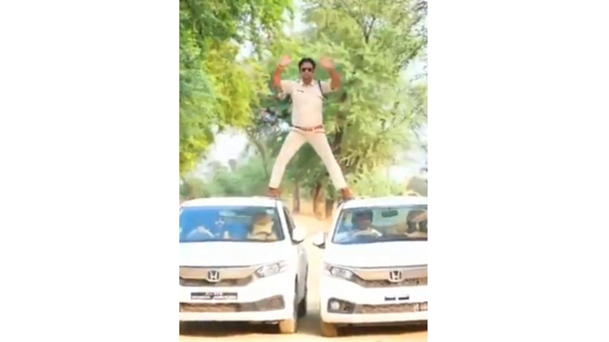 Manoj Yadav, the in-charge of Narsinghgarh police post in Damoh district performs a daredevil act of balancing himself on two moving cars. (Twitter video screengrab)