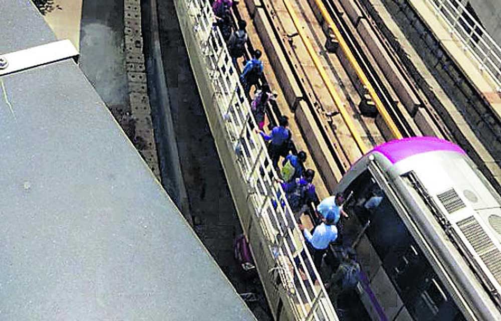 Passengers walk on the emergency walkway to reach Byappanahalli Metro Station after a technical glitch halted the train near Swami Vivekananda Metro station on Monday. DH Photo