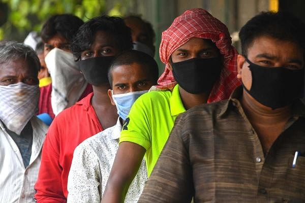 Migrant workers gather outside a police station to take a bus directed to a railway terminus for boarding a special train during a nationwide lockdown imposed as a preventive measure against the COVID-19 coronavirus, in Mumbai on May 18, 2020. (AFP Photo) 