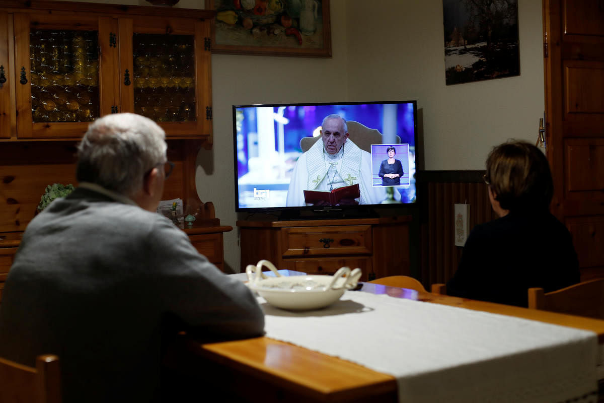 People watch the extraordinary ''Urbi et Orbi'' (to the city and the world) blessing of Pope Francis at TV, in Cisternino, Italy, March 27, 2020. REUTERS/Alessandro Garofalo
