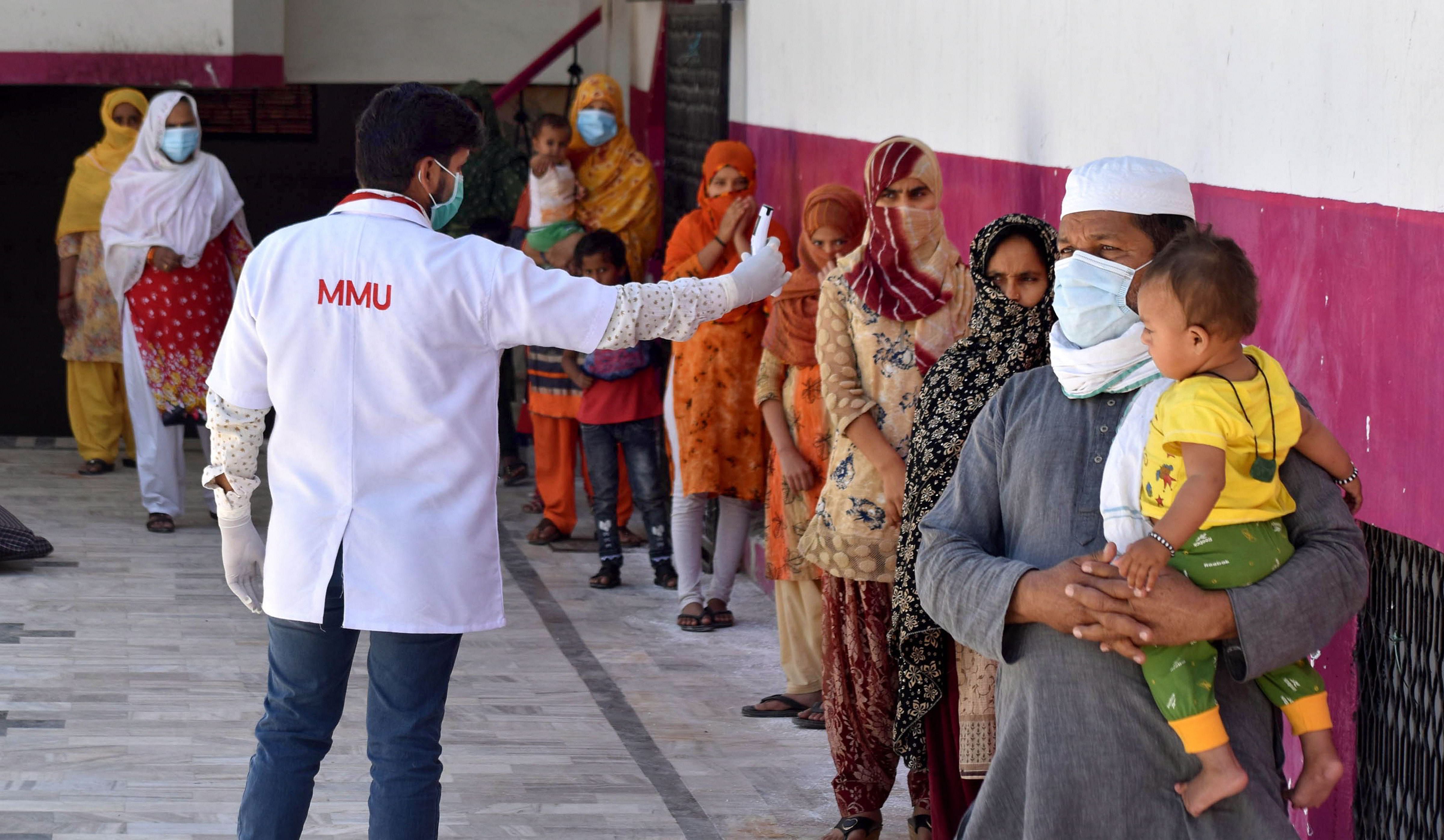 A medics checks the temperature of attendees of a religious congregation in Delhi's Nizamuddin area during their isolation period at a COVID 19 quarantine facility in Prayagraj. (PTI Photo)