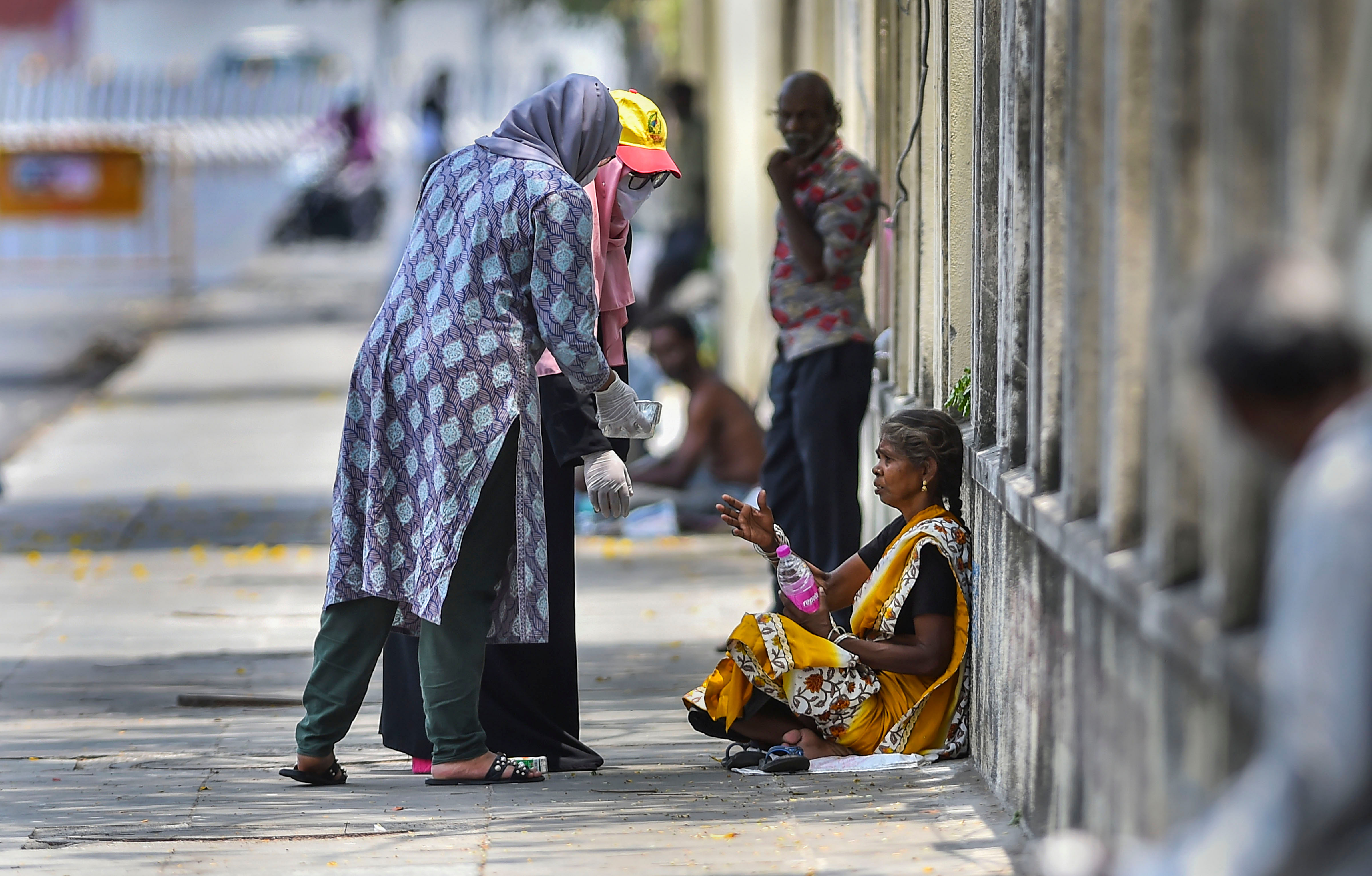 Two women offer food to a poor woman during the nationwide lockdown imposed to contain the spread of the COVID-19. (PTI Photo)
