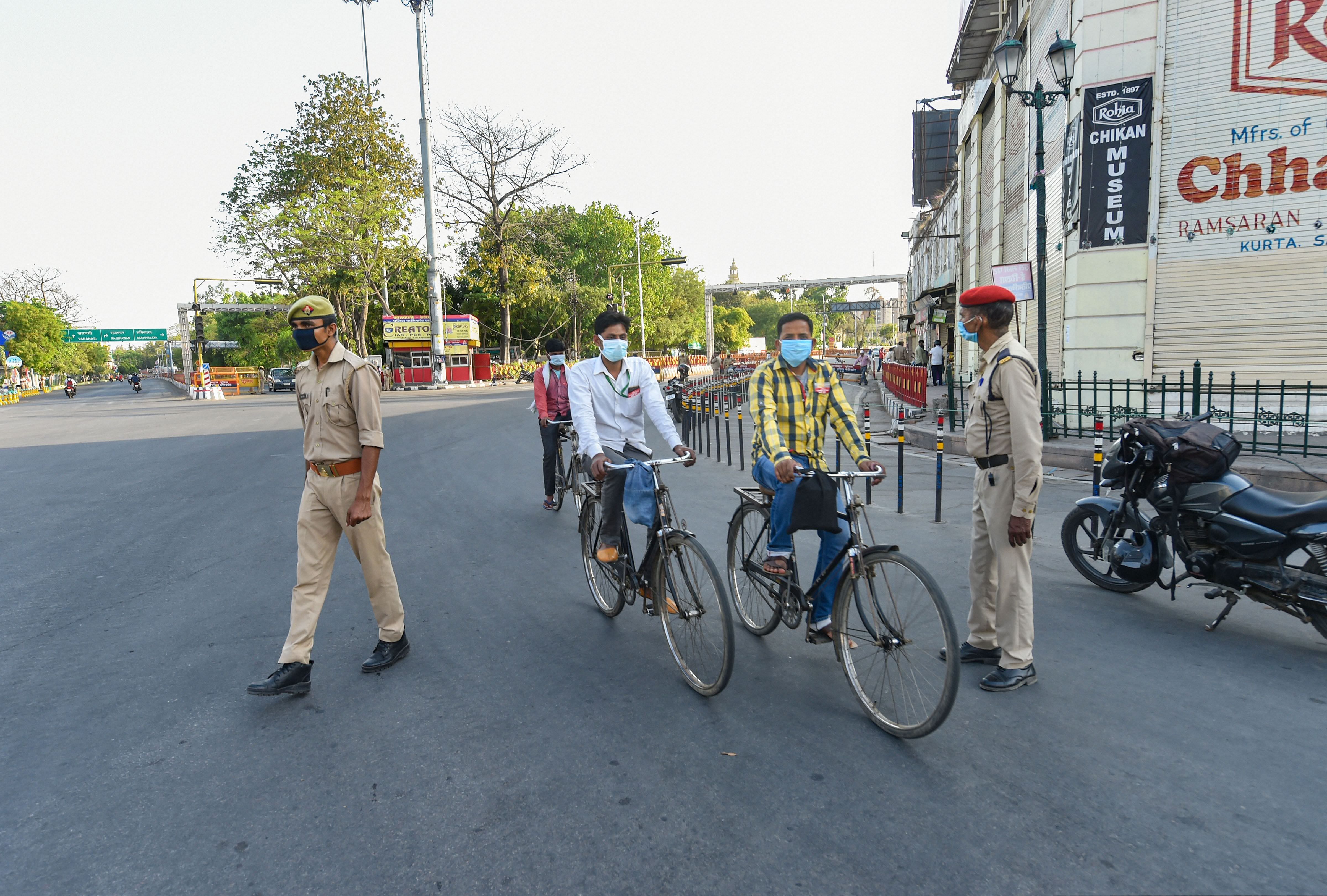  Two cyclists move past as policemen stand guard during the nationwide coronavirus lockdown, in Lucknow. (Credit: PTI Photo)