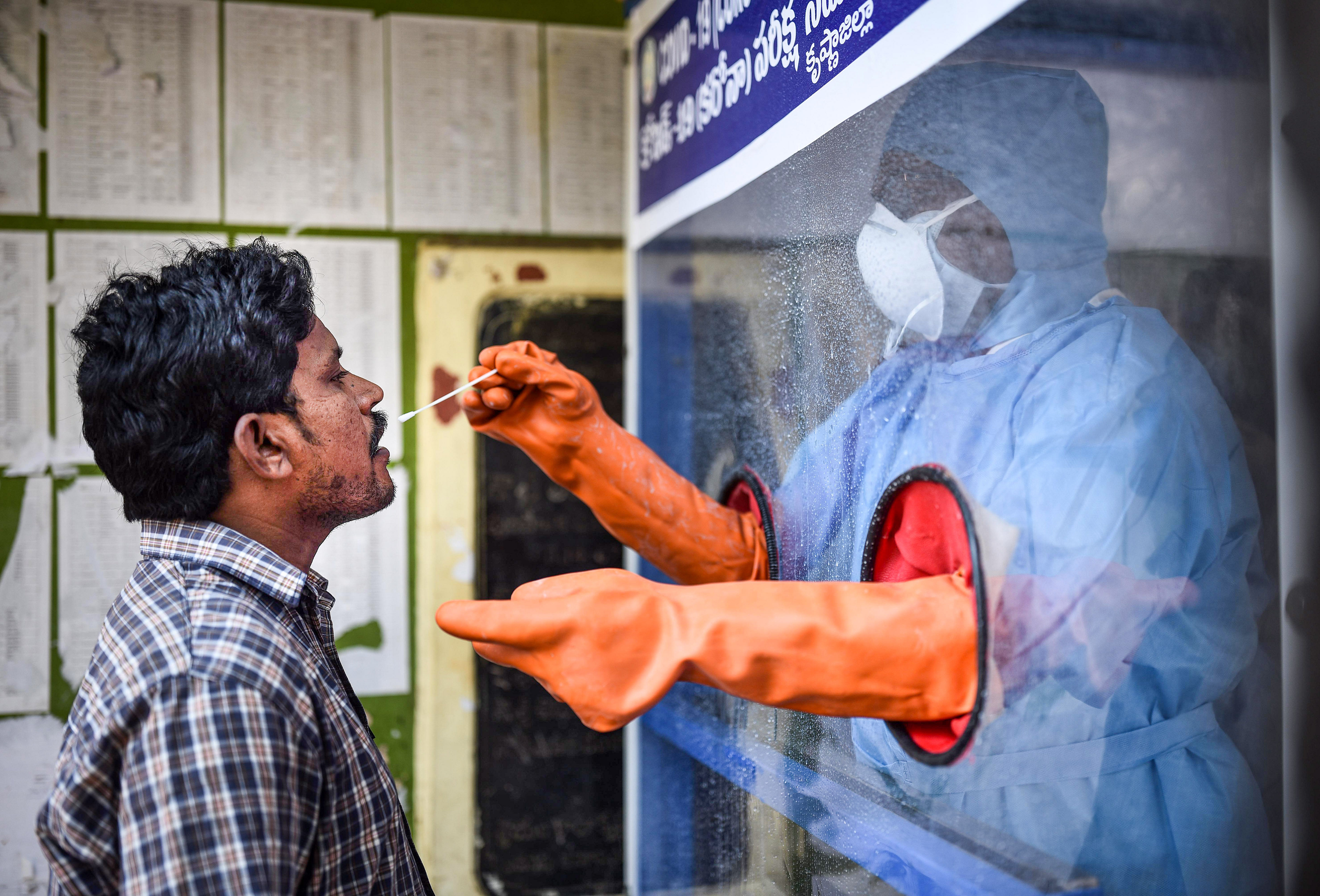 Vijayawada: A healthcare worker collects a swab sample of a man for COVID-19 test from the swab collection booth (PTI photo)