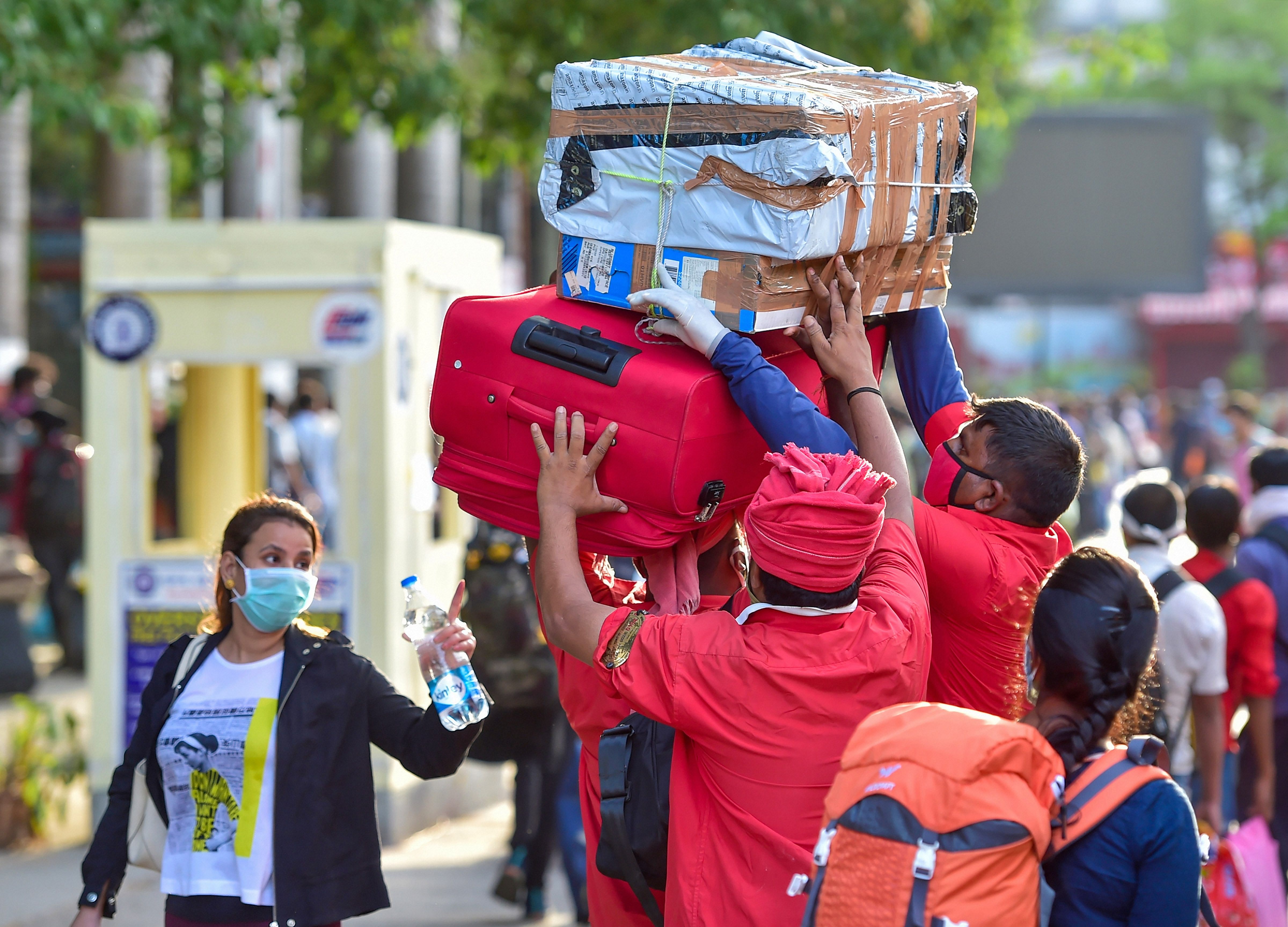 Railway porters (coolie) carry luggage of passengers arriving at a railway station to board the special train to New Delhi after the resumption of passenger train services by the Indian Railways in a graded manner amid ongoing COVID-19 lockdown, in Bengaluru. (PTI Photo)