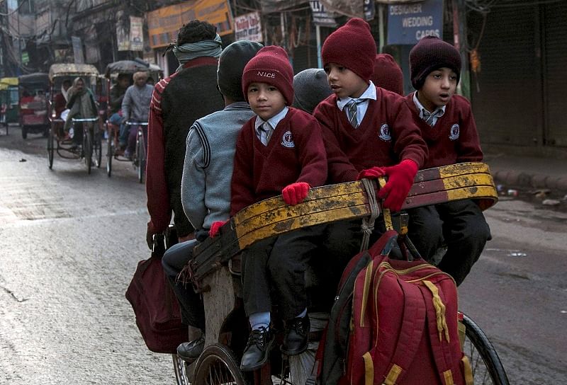 School children travel to school in a cycle rickshaw on a cold winter morning in the old quarters of Delhi. (PTI Photo