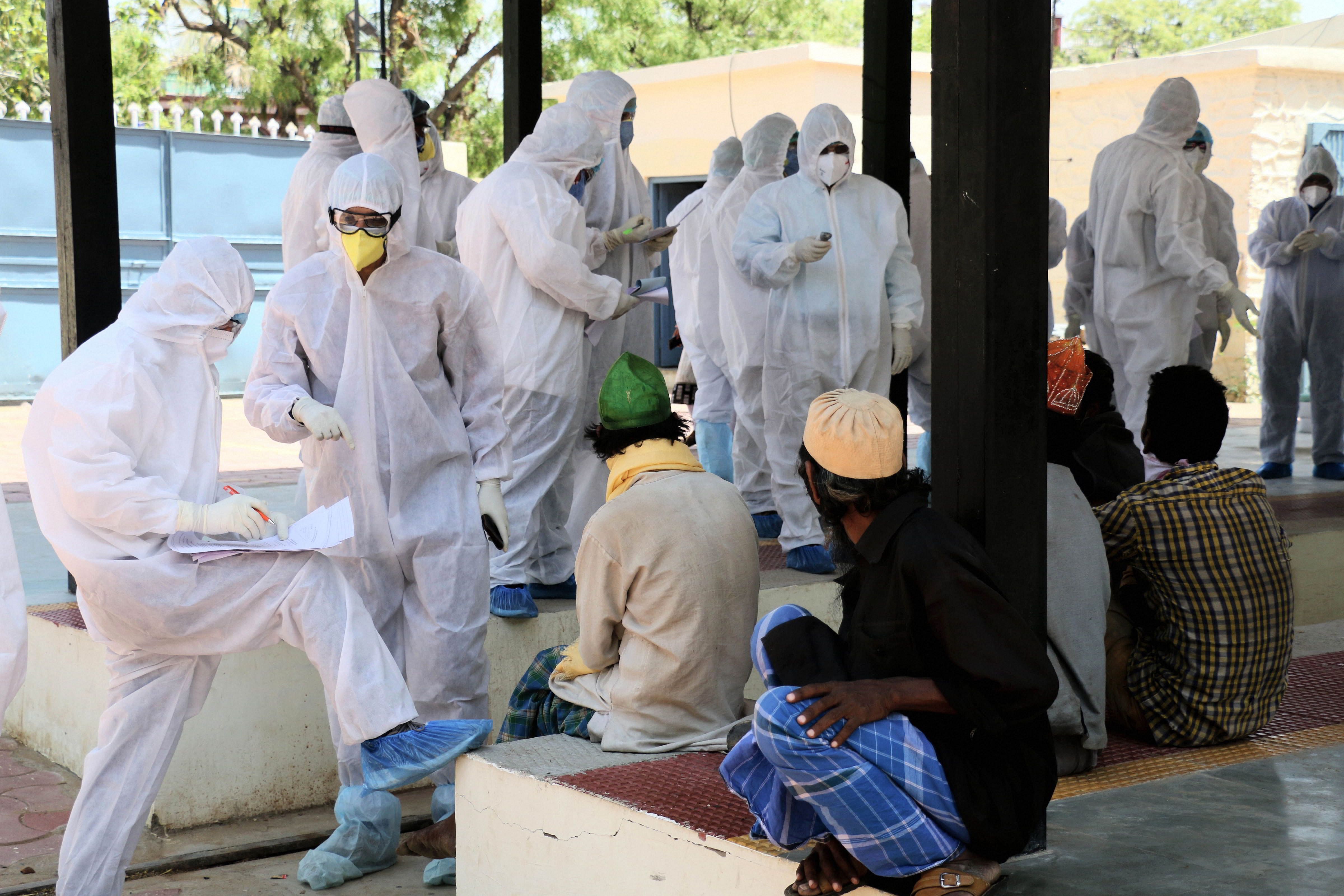 Medics collect swab from mouths of people for COVID-19 test after a person was found positive for the novel coronavirus at Rail Museum shelter home. (Credit: PTI Photo)